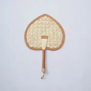 Hand-woven straw fan detail, natural woven texture with edge binding and handle loop design.