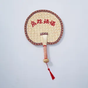 Handmade woven straw fan Chinese style summer hand-held cattail leaf fan with red tassel detail.