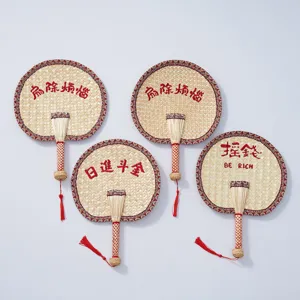 Handmade woven straw fan detail shot showcasing traditional Chinese cooling fan design and red tassels.