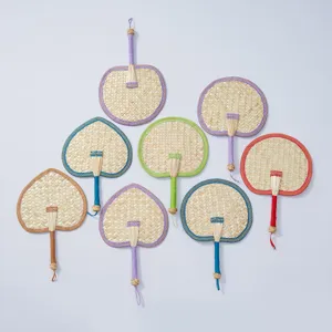 Handmade woven straw fan with colorful borders, traditional summer cooling hand fan detail.