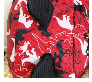 Red toddler dinosaur backpack detail showing cute 3D spikes and cartoon print for kids use.