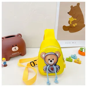 Detailed view of a bright yellow children sling bag with cute bear print and strap.
