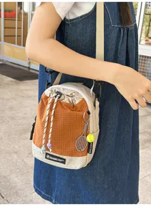 Detail view of the lightweight outdoor crossbody bag with drawstring and tennis pendant.