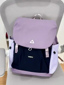 Detail shot of the stylish dual-color backpack on a chair, showing pockets and straps.
