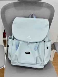 Light blue backpack detail showing flap closure, drawstring, and front brand label.