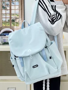 Detail view of light blue casual backpack with flap closure, multi pockets and soft straps.