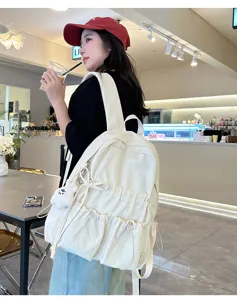 Niche design white pleated backpack with cute bow drawstring and plush pendant detail view.