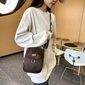 Vue détaillée d'un sac bandoulière marron en nylon avec anneau métallique en café.