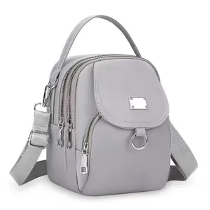 Détail du mini sac à dos gris en tissu Oxford avec multiples poches zippées pratiques.
