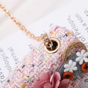 Pink tweed children shoulder bag detail, cute floral decor, gold chain strap texture.