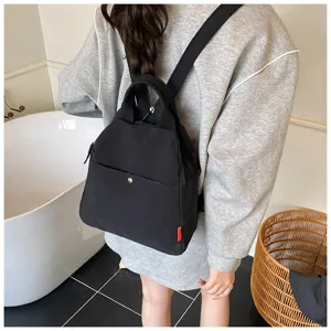 Casual black backpack detail view, minimalist daily commuting travel bag with top handle.