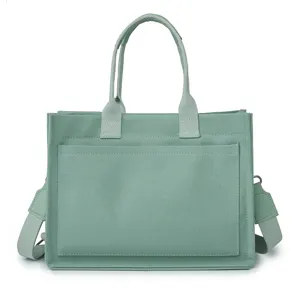 Sage green canvas tote bag detail view, showing front pocket and durable handle construction.