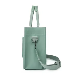 Detailed side view of sage green canvas tote bag featuring dual handles and shoulder strap.