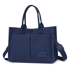 Detailed view of the dark blue canvas tote bag with front pockets and shoulder strap.