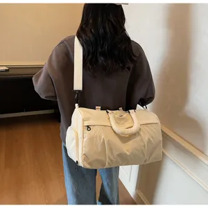 Detail view of a stylish beige travel duffel bag showing its spacious capacity and strap.