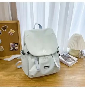 Detail view of light green casual backpack featuring flap drawstring design and brand patch.