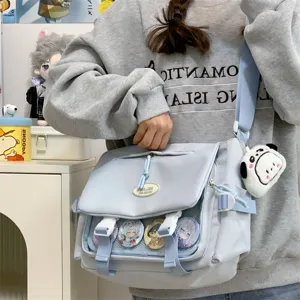 Light blue ita bag detail showing transparent front window, badges and cute plush charm pendant.