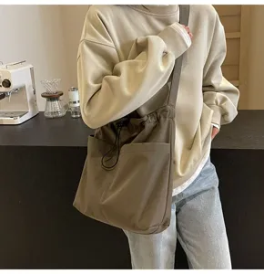 Minimalist solid color nylon bucket bag, casual outdoor crossbody bag with drawstring design.