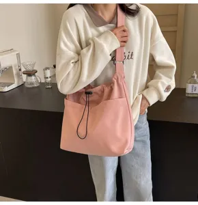 Pink nylon bucket bag detail showing drawstring closure and front pocket design. Suitable for daily use.