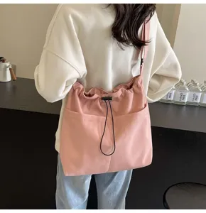 Close-up detail of stylish pink nylon crossbody bucket bag with drawstring and front pockets
