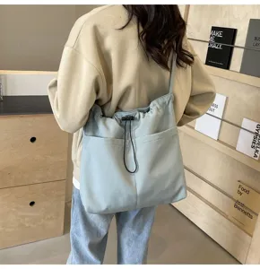 Casual light blue nylon shoulder bag scene detail, showing drawstring and front pockets.