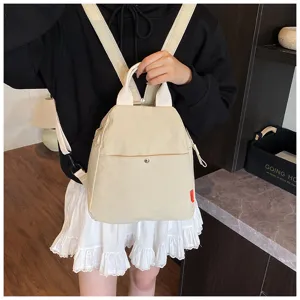 Detail view of the stylish beige minimalist backpack featuring front pocket and adjustable straps.