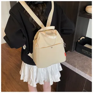 Detail view of the minimalist beige canvas backpack showing back strap and front.