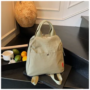 Casual nylon backpack detail view, minimalist candy color commuting bag with top handle and pocket.