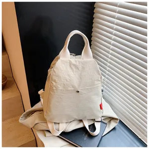 Minimalist canvas backpack detail showcasing neutral beige tone, sturdy straps, and stylish hardware.