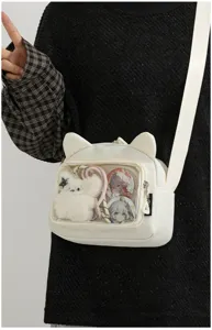 Detailed view of white cute cat ear ita bag with clear window, anime badges and plush pendant.