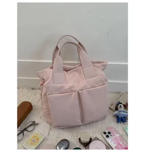 Casual pink nylon tote bag detail, featuring dual top handles and spacious front pockets.