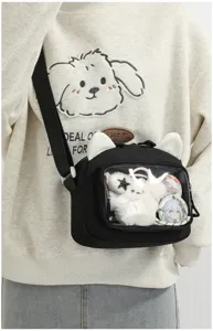 Detail view of a cute black ita bag with cat ears and clear window showing anime badges.