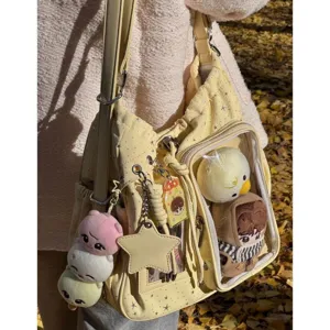 Clear front pocket ita bag detail showcasing cute plush dolls and star print design in yellow.