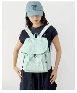 Detailed view of light green crinkle nylon backpack, casual outdoor camping style accessory.