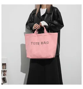 Detailed view of the pink tote bag with stylish studded lettering handle and spacious design.