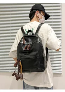 Detail view of black PU leather backpack with front crocodile pattern pocket and cute dog charm.
