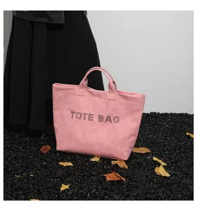 Detail shot of the pink letter tote bag showing textured fabric and studded TOTE BAG text.