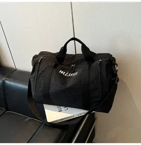Détail de sac de voyage noir, tissu résistant, poignées robustes et grand compartiment.