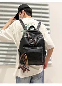 Detailed view of black PU leather backpack with crocodile texture pocket and cute dog charm.