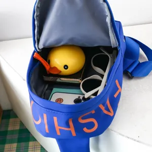 Children blue chest bag detail showing internal storage capacity and cute duck toy props inside.