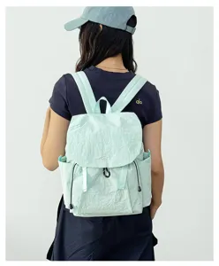 Detailed back view of a light green nylon backpack with front pockets and drawstrings.