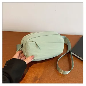 Light green nylon belt bag detail showing zipper pocket, adjustable strap and clean texture.