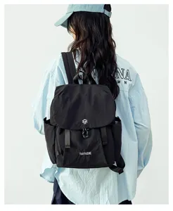 Detail view of the black lightweight travel backpack with flap, drawstring, and side pockets.