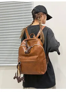 Detailed view of brown PU leather backpack featuring crocodile pattern pocket and charm.