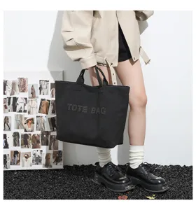 Black canvas tote bag for women, large capacity shoulder handbag with stylish stud lettering design.