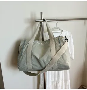 Vue détaillée du sac de voyage décontracté vert clair suspendu sur le portant avec sangle.