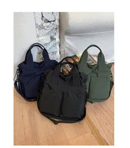 Detail view of casual nylon tote shoulder bags in multiple colors, featuring dual front pockets.