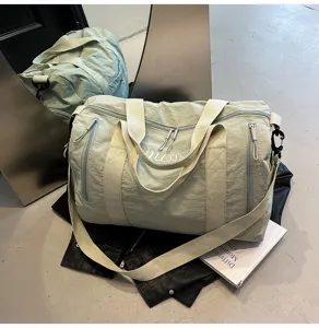 Vue détaillée du sac de voyage vert clair en tissu résistant avec des poches pratiques.