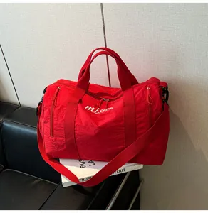 Detail du sac de voyage rouge, grand sac de sport en nylon avec bandouliere reglable.