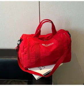 Grand sac de voyage rouge détail montrant le tissu en nylon et la poche zippée latérale.